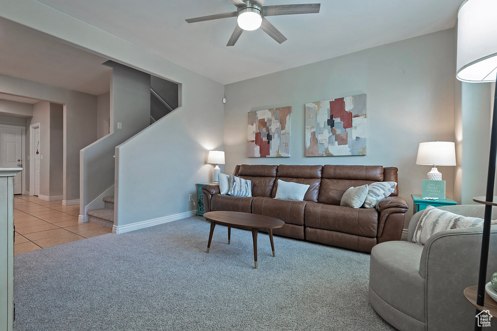 Living room featuring a ceiling fan, stairway, baseboards, light carpet, and light tile patterned flooring