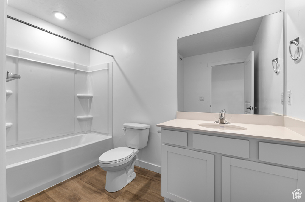Full bath featuring toilet, wood finished floors, shower / bath combination, baseboards, and vanity