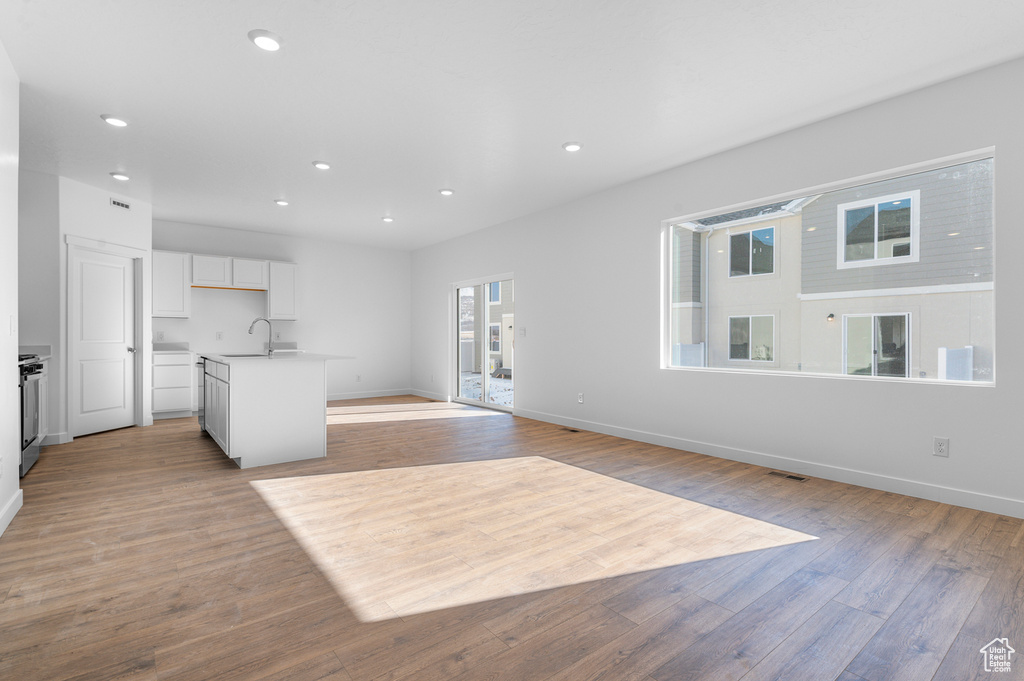 Unfurnished living room with light wood-style flooring, recessed lighting, baseboards, and a sink