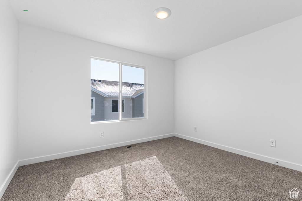 Carpeted empty room with visible vents and baseboards