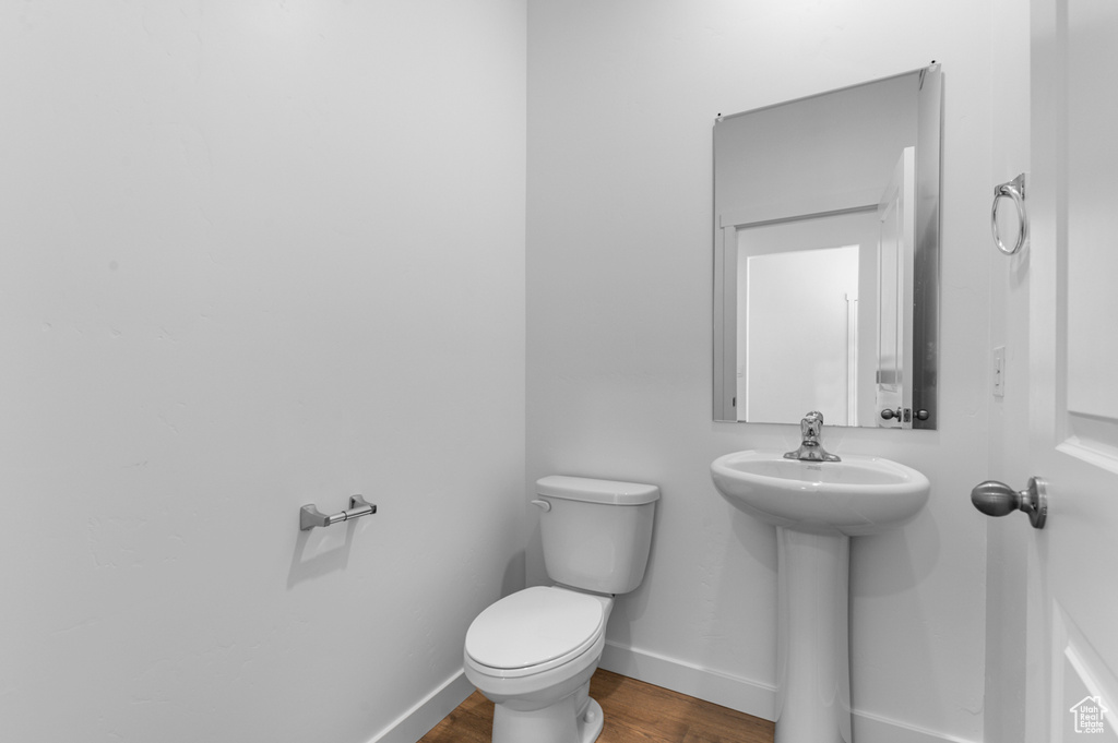 Half bathroom featuring toilet, wood finished floors, and baseboards