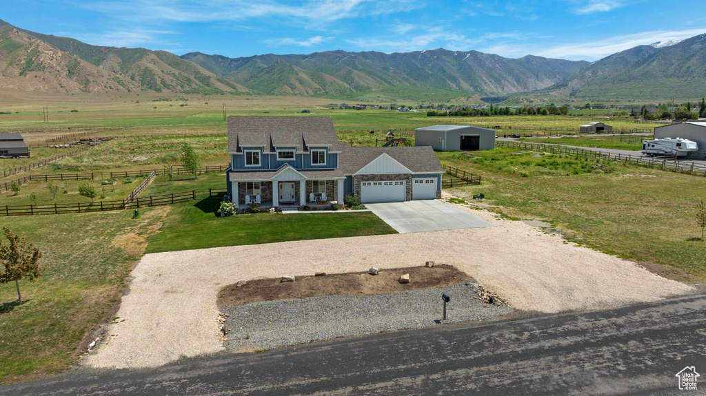 View of front of home with a garage, driveway, covered porch, a view of countryside, and a mountain view