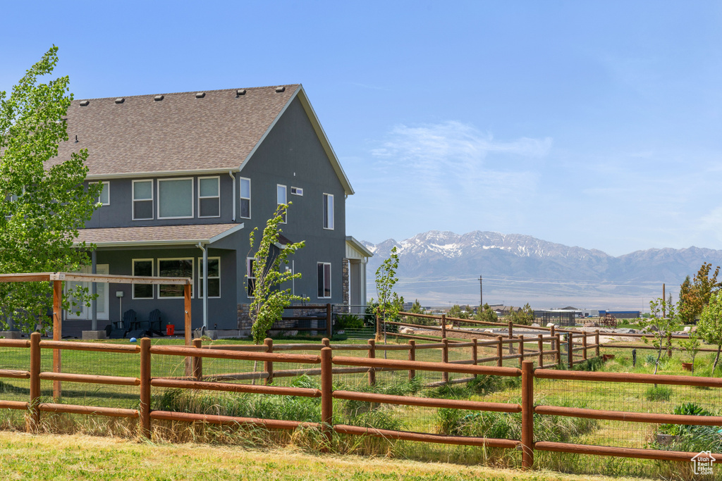 Rear view of house with a shingled roof, a mountain view, a view of rural / pastoral area, and fence