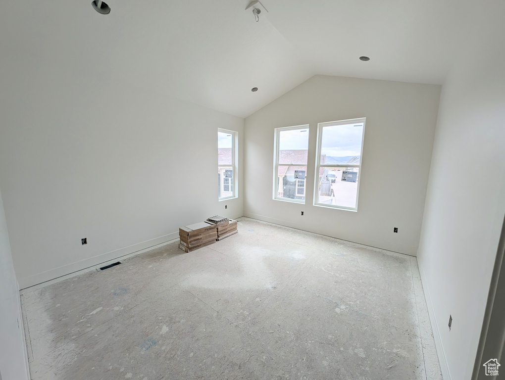 Spare room featuring vaulted ceiling and baseboards
