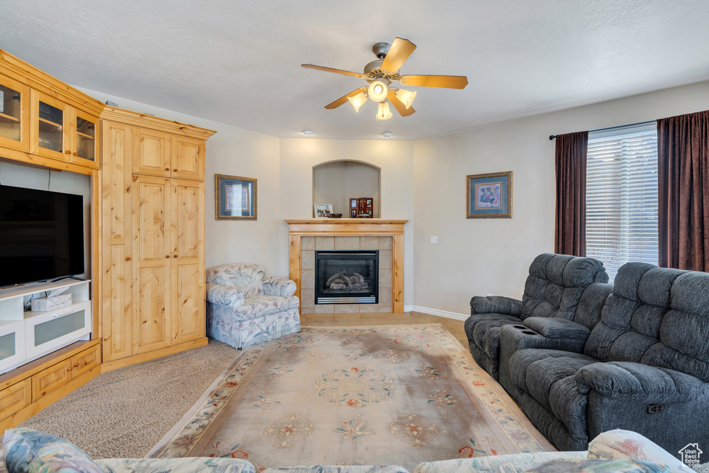 Living room with ceiling fan, carpet, baseboards, and a fireplace