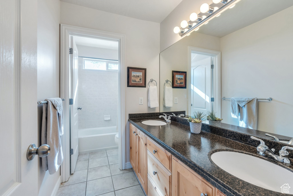 Bathroom with toilet, double vanity, a sink, and tile patterned flooring