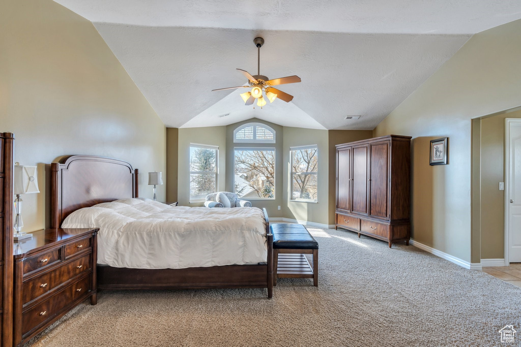 Bedroom with ceiling fan, visible vents, vaulted ceiling, light carpet, and baseboards