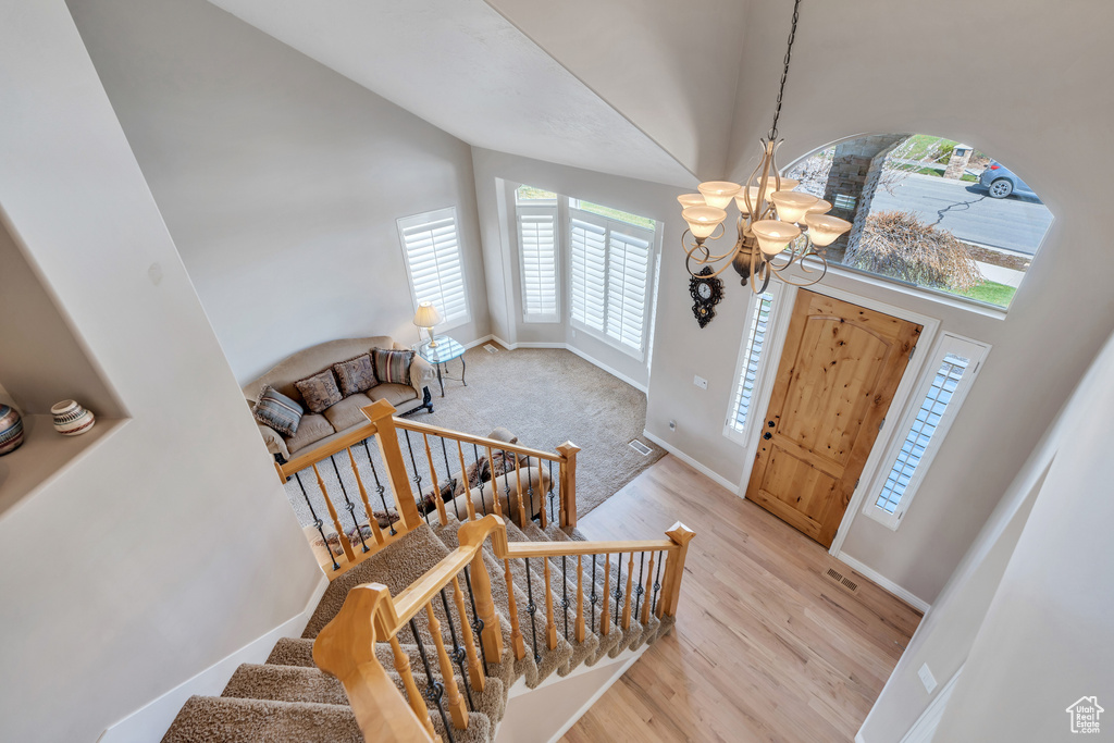 Foyer with visible vents, high vaulted ceiling, an inviting chandelier, and light wood-style floors