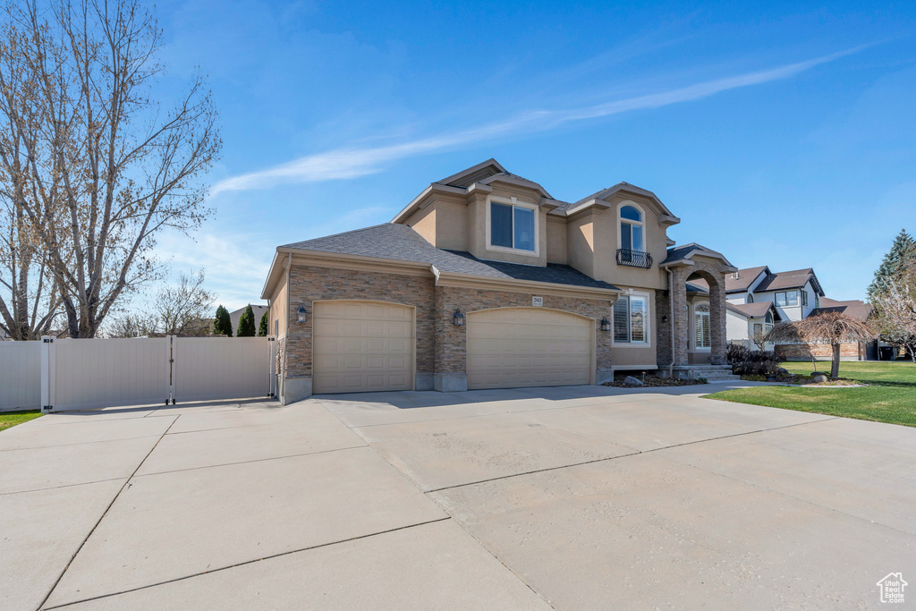 View of front of house featuring stucco siding, fence, a front lawn, a gate, and driveway