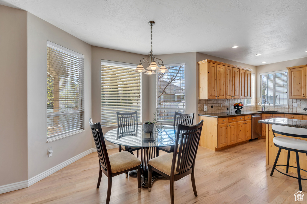 Dining space featuring a chandelier, light wood finished floors, baseboards, and recessed lighting