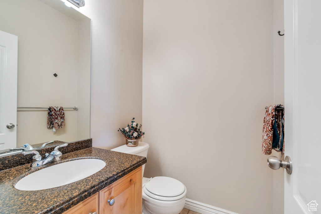 Bathroom featuring toilet, vanity, and baseboards