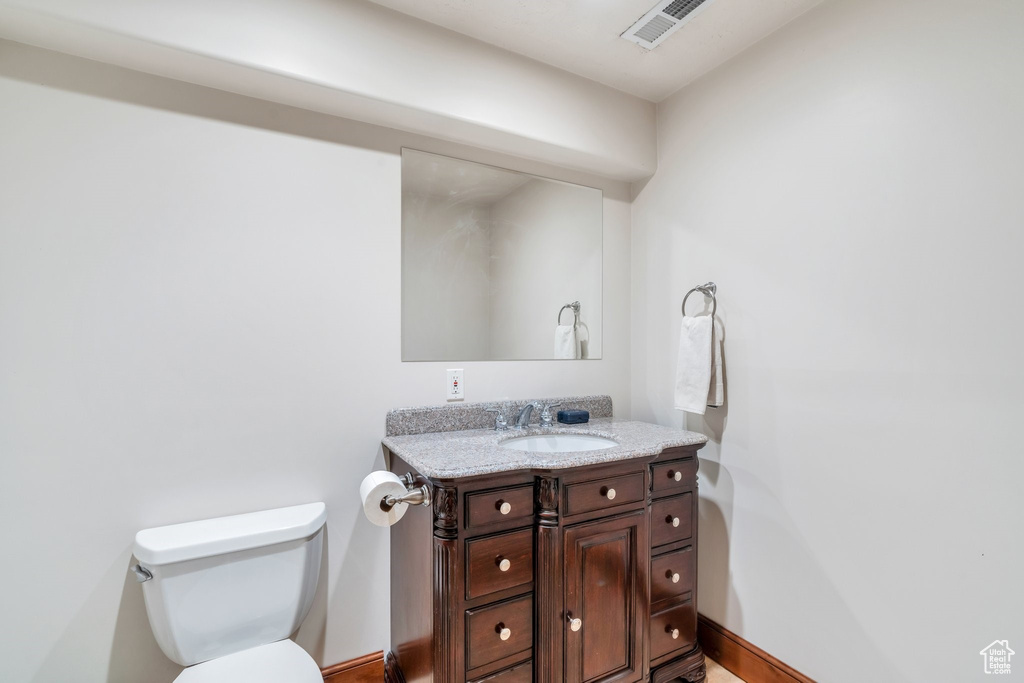 Bathroom featuring visible vents, toilet, vanity, and baseboards