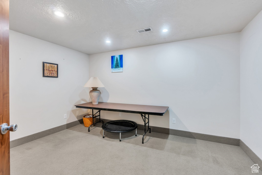Carpeted office space featuring visible vents, baseboards, recessed lighting, and a textured ceiling