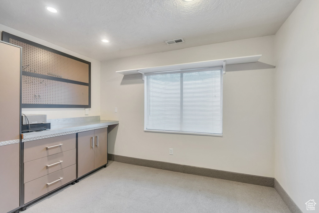 Interior space featuring gray cabinetry, visible vents, light colored carpet, and baseboards