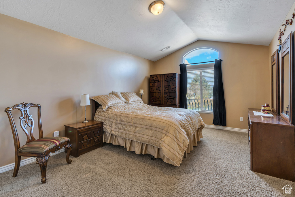 Bedroom with baseboards, vaulted ceiling, a textured ceiling, visible vents, and light colored carpet