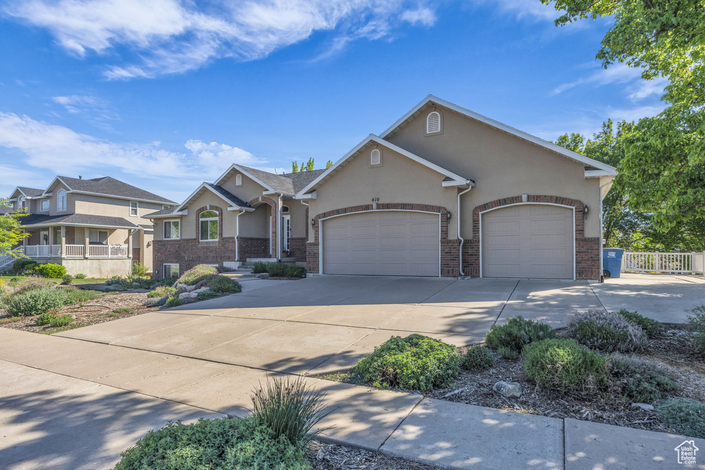 View of front facade featuring a garage, stucco siding, concrete driveway, and fence