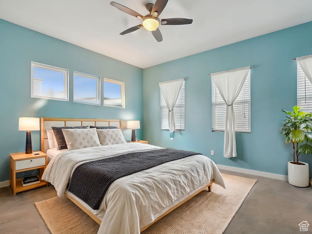 Carpeted bedroom featuring multiple windows, baseboards, and ceiling fan
