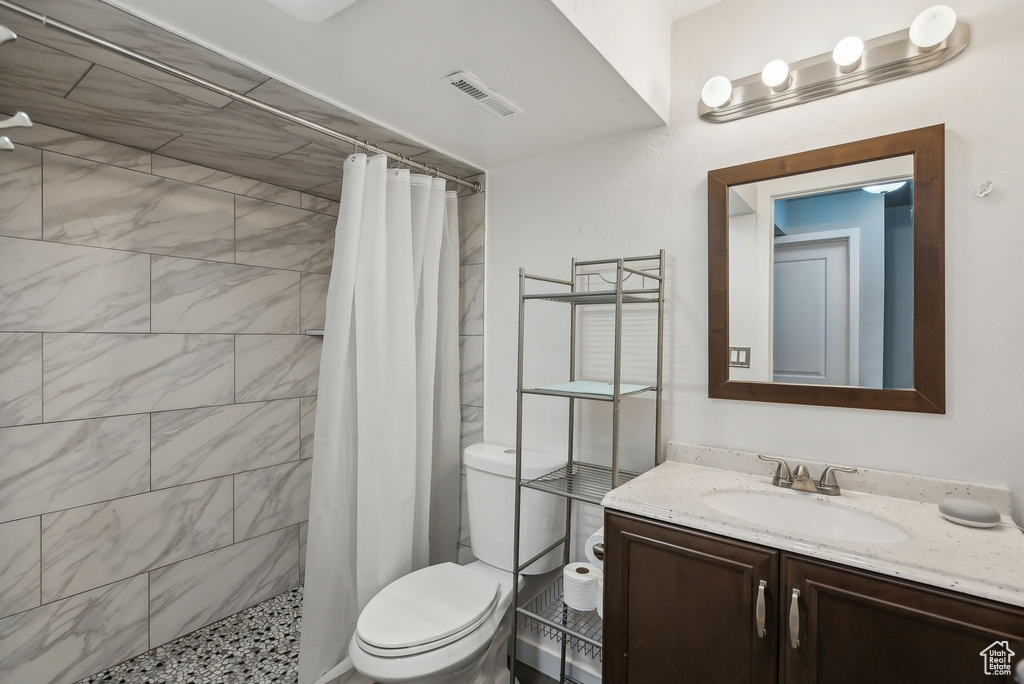 Bathroom featuring vanity, toilet, visible vents, and tiled shower