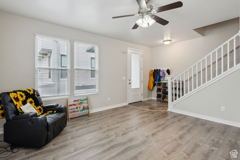 Foyer entrance featuring a ceiling fan, stairs, baseboards, and wood finished floors