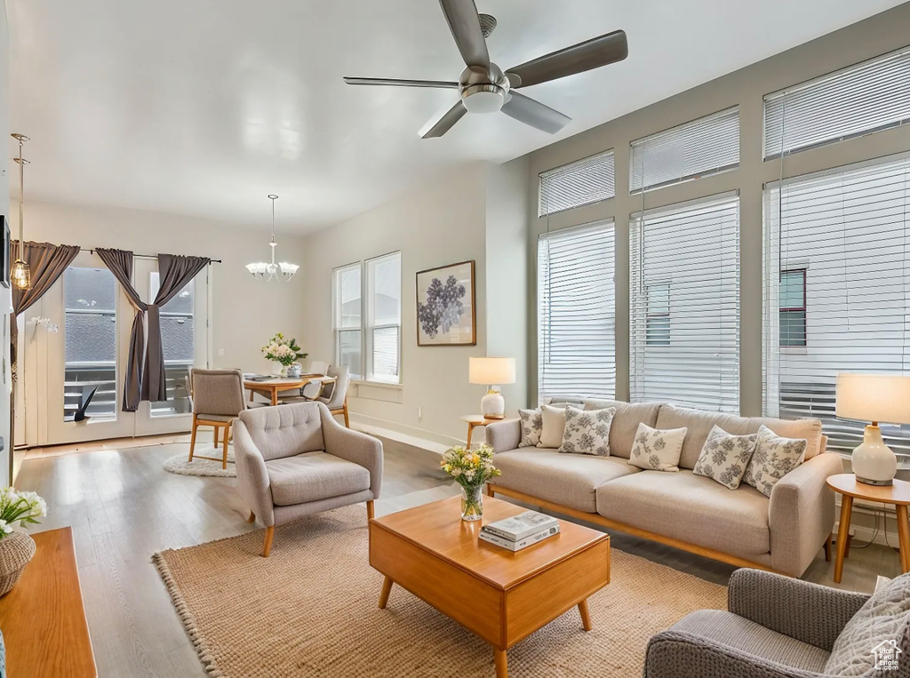 Living area with baseboards, wood finished floors, and ceiling fan with notable chandelier