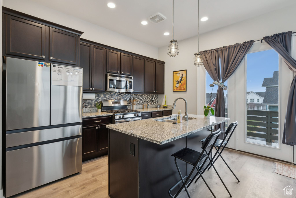 Kitchen with light stone countertops, visible vents, a sink, decorative backsplash, and stainless steel appliances