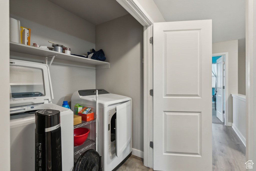 Laundry room with independent washer and dryer, laundry area, wood finished floors, and baseboards
