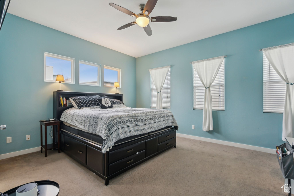 Bedroom with light carpet, ceiling fan, and baseboards
