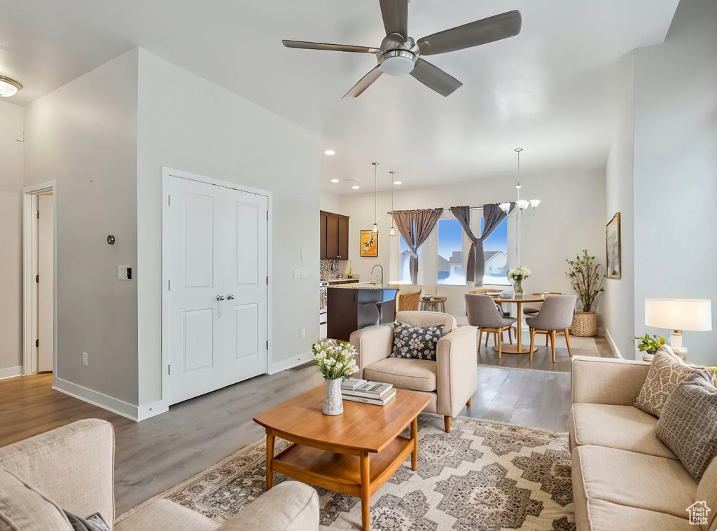 Living room featuring baseboards, wood finished floors, and ceiling fan with notable chandelier