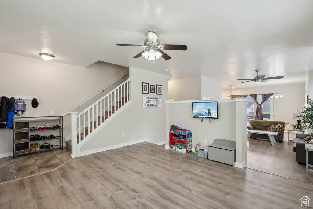 Living room featuring wood finished floors, stairway, a ceiling fan, and baseboards