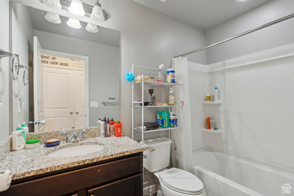Bathroom featuring toilet, vanity, and shower / tub combo