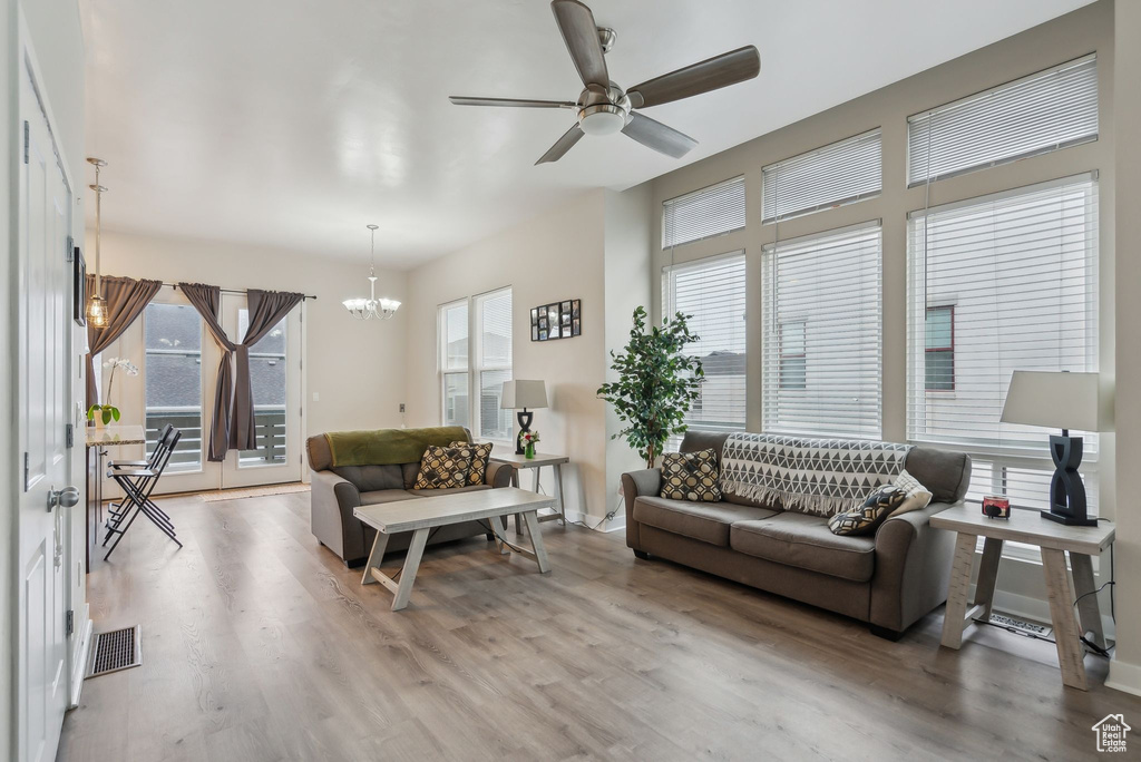 Living room featuring ceiling fan with notable chandelier, wood finished floors, visible vents, and a healthy amount of sunlight