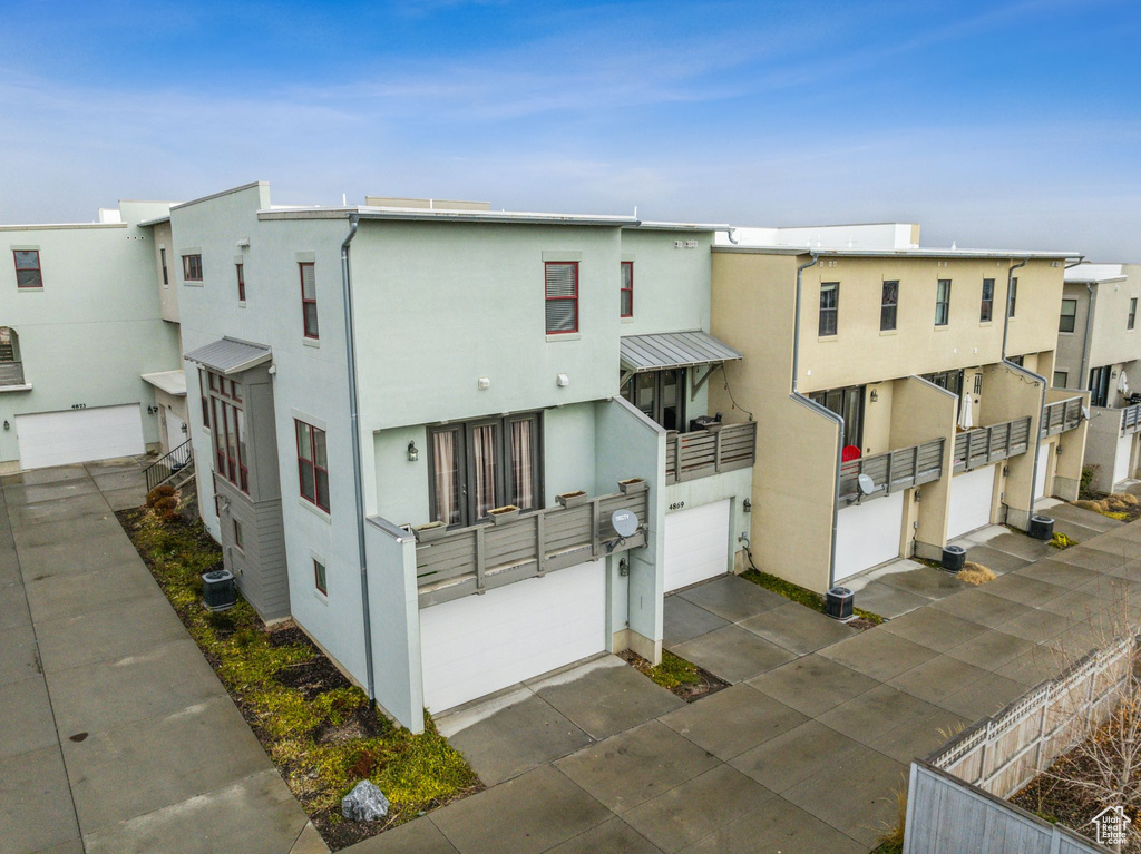 Exterior space with central AC, concrete driveway, an attached garage, and fence