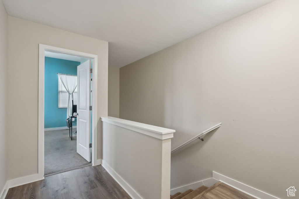 Corridor with an upstairs landing, baseboards, and wood finished floors