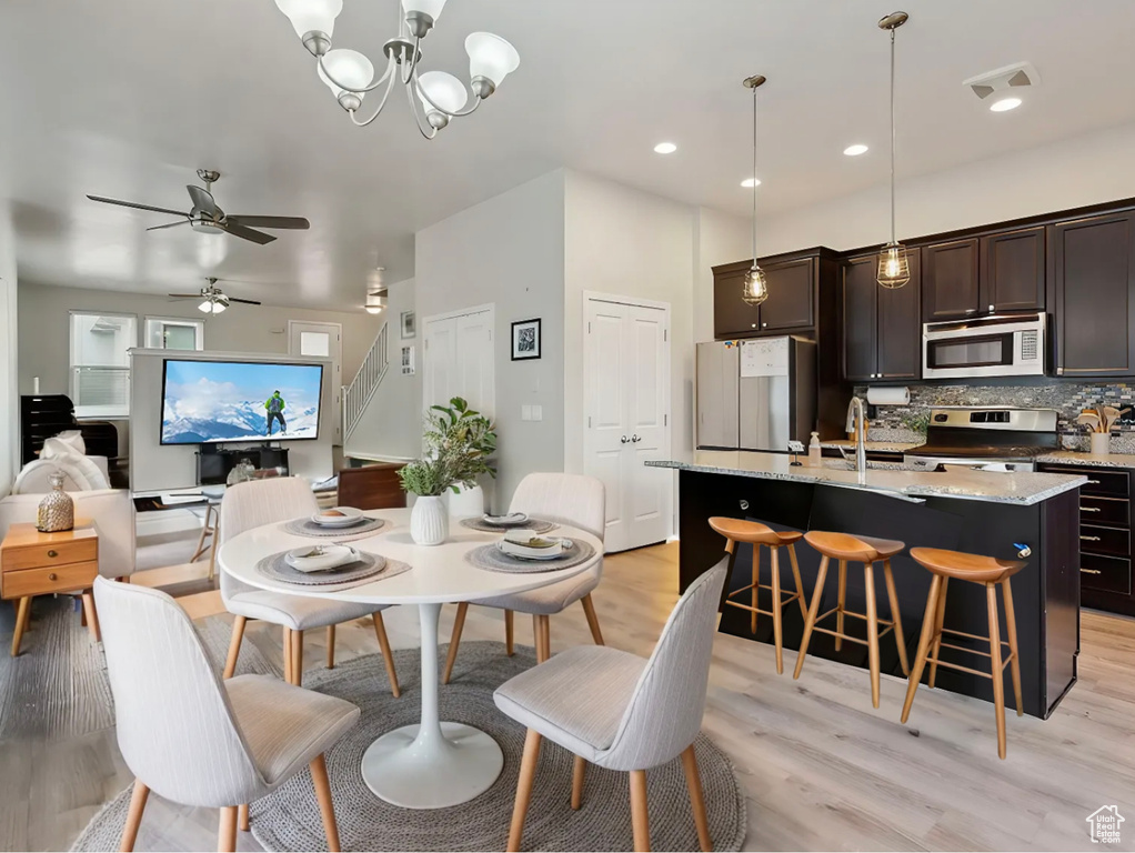 Dining room featuring visible vents, recessed lighting, stairs, light wood-style floors, and ceiling fan with notable chandelier