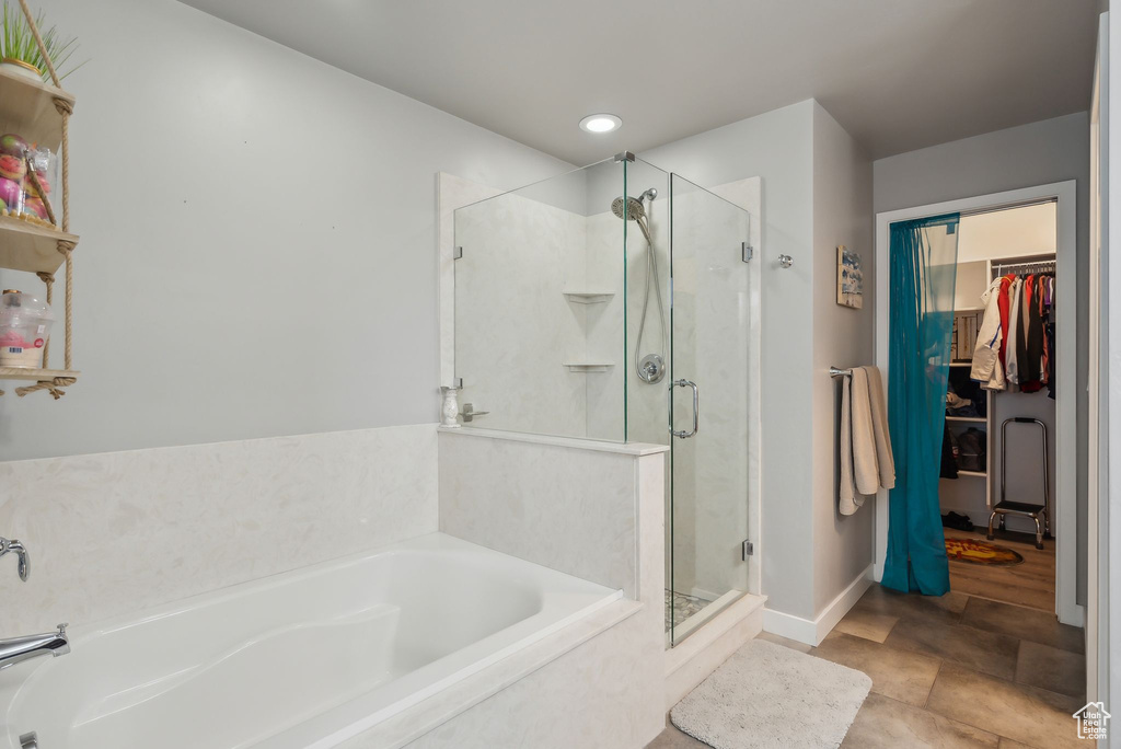 Full bath featuring baseboards, recessed lighting, a shower stall, a walk in closet, and a garden tub
