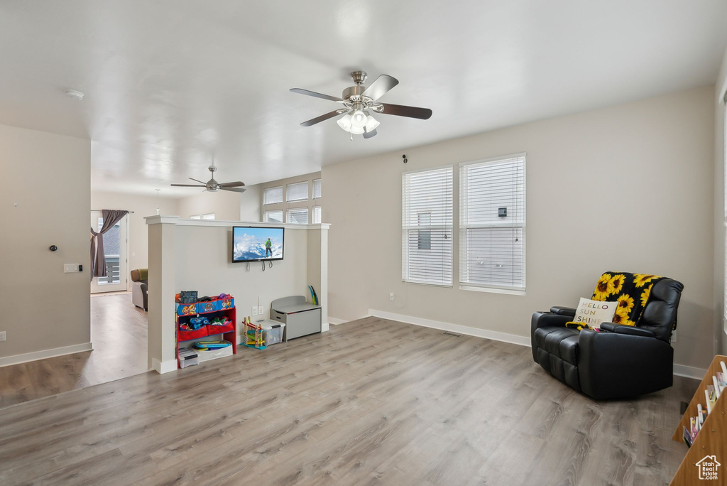 Sitting room with baseboards, a ceiling fan, and wood finished floors