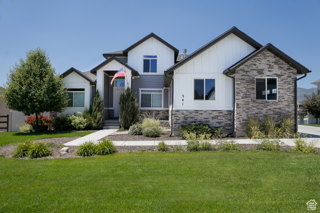 Craftsman-style house featuring stone siding, board and batten siding, and a front lawn