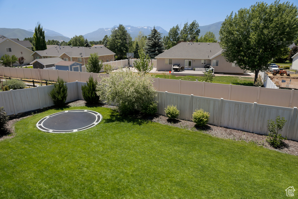Fenced backyard with a mountain view, a trampoline, and a residential view