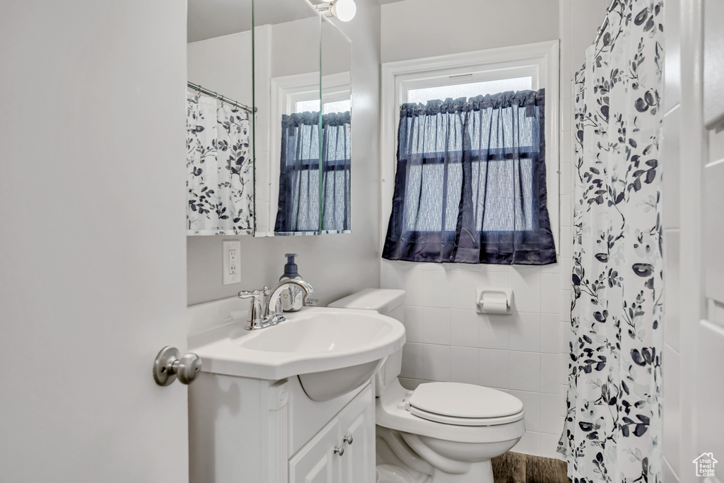 Full bathroom featuring vanity, tile walls, and a shower with shower curtain