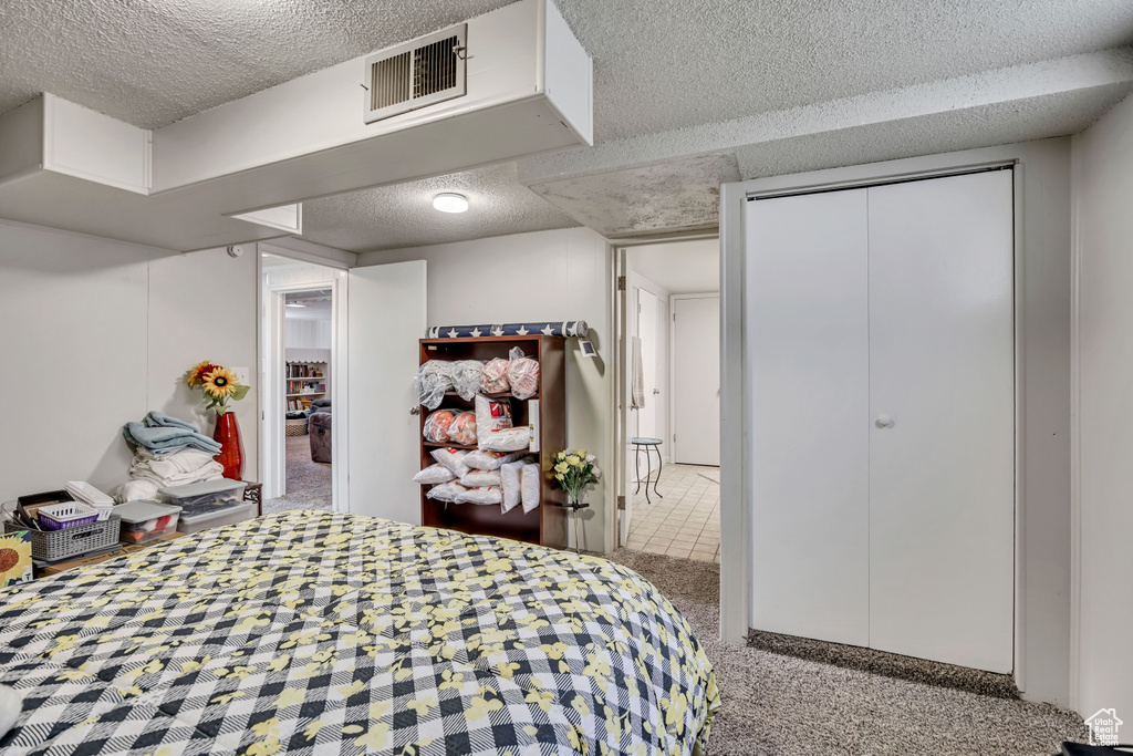 Carpeted bedroom with a textured ceiling and a closet