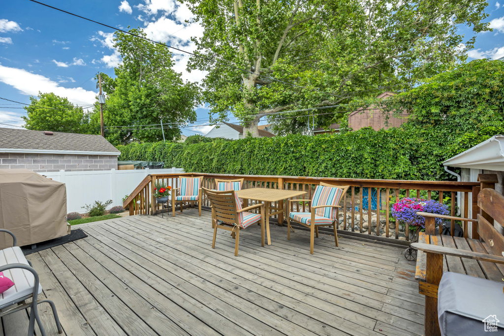 Wooden terrace with a grill, a fenced backyard, and outdoor dining space