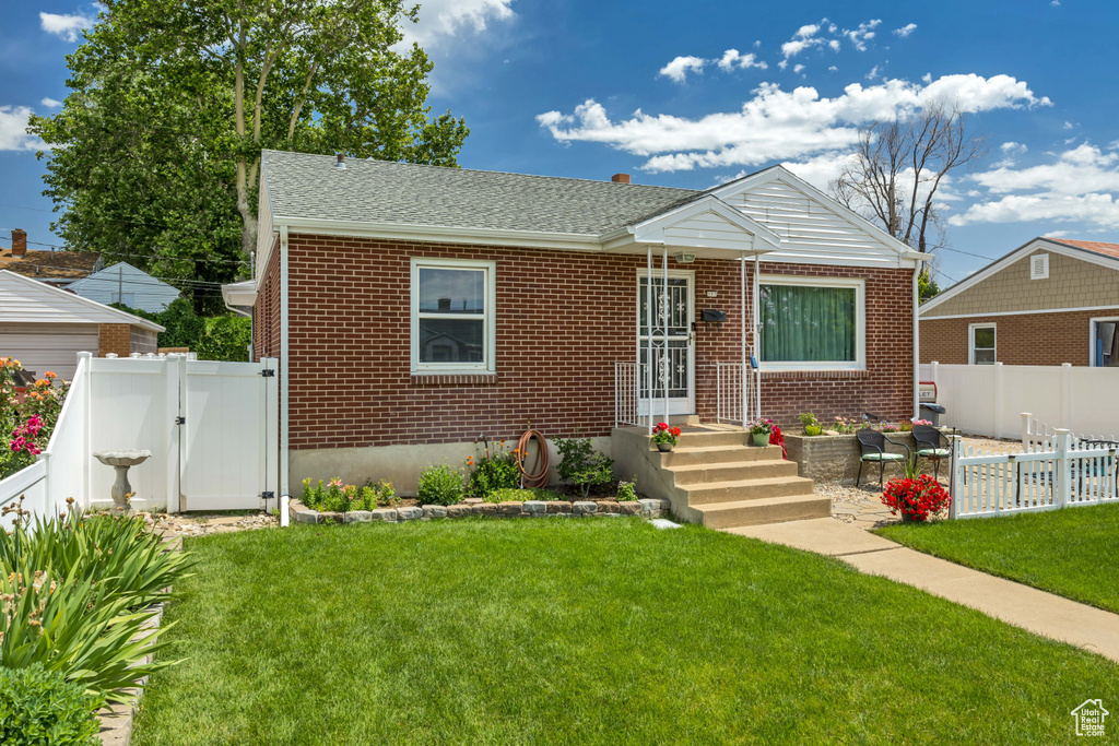 Bungalow-style house with a gate, brick siding, and a fenced backyard