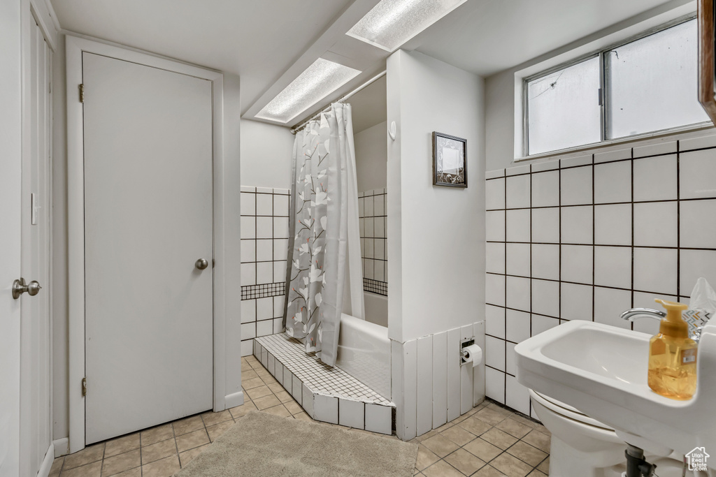 Full bathroom featuring tile walls, a tile shower, and tile patterned flooring