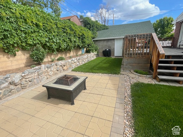 View of yard featuring an outdoor fire pit, a wooden deck, and a patio