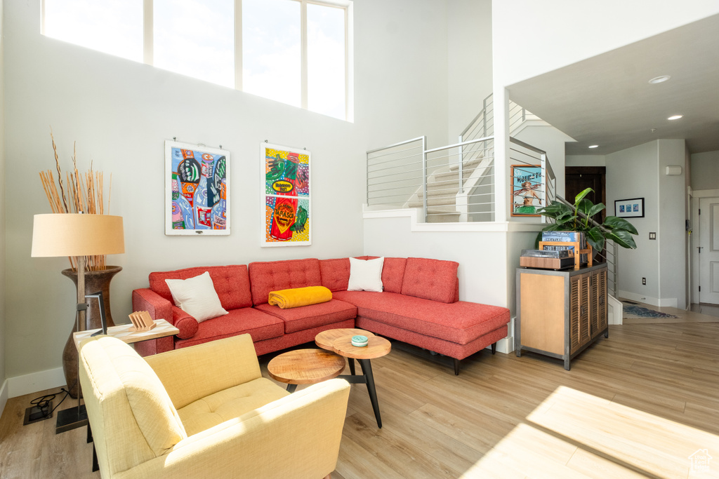 Living area featuring light wood-style floors, stairway, a towering ceiling, baseboards, and recessed lighting