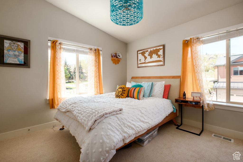 Bedroom with multiple windows, lofted ceiling, carpet, and baseboards
