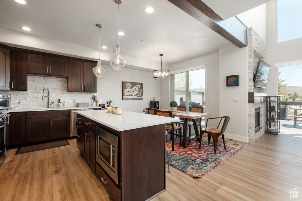 Kitchen featuring stainless steel microwave, a sink, light countertops, light wood finished floors, and decorative backsplash