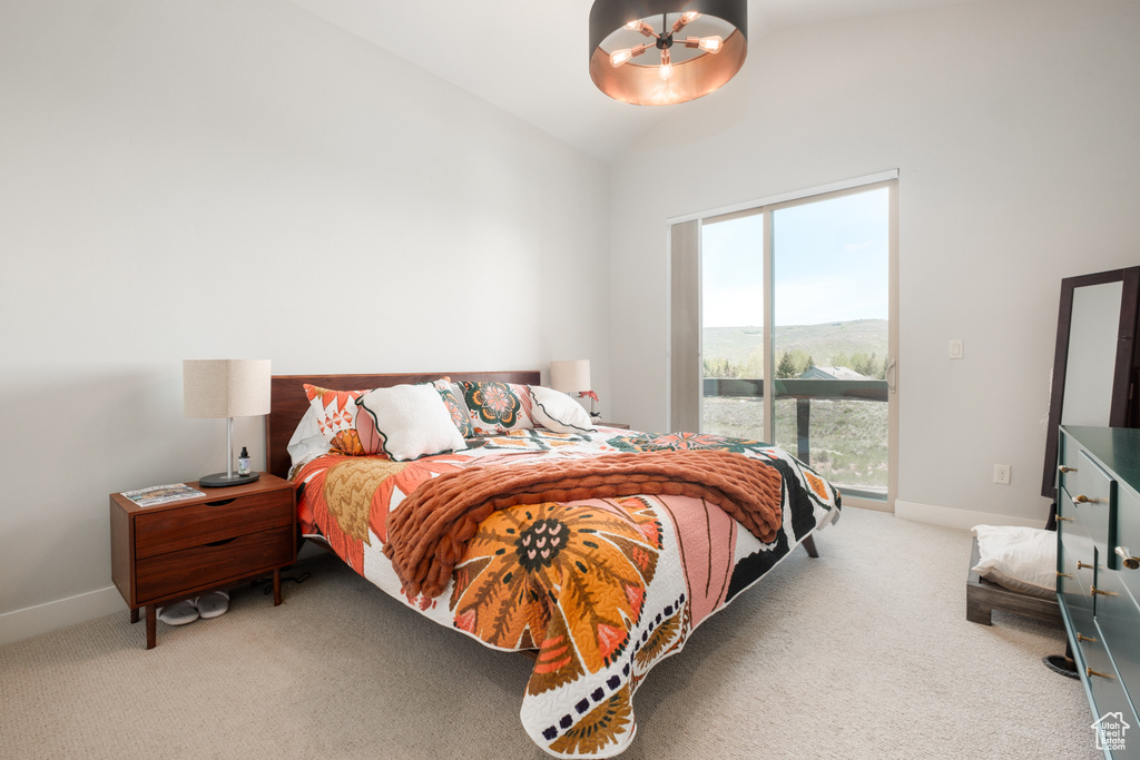 Carpeted bedroom with access to outside, a chandelier, vaulted ceiling, and baseboards
