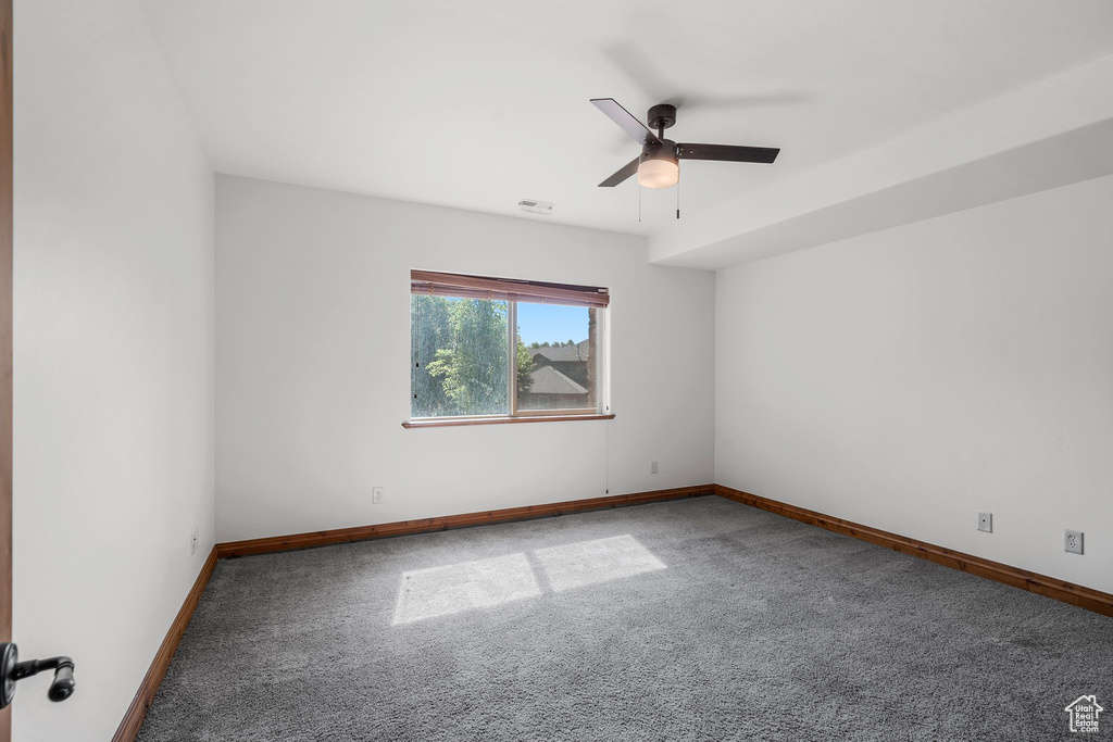 Carpeted spare room with ceiling fan and baseboards