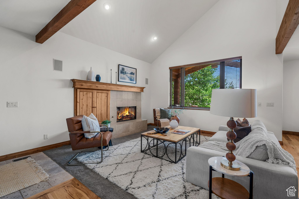 Living area featuring high vaulted ceiling, wood finished floors, a tiled fireplace, recessed lighting, and beamed ceiling